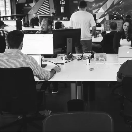 Employees in an office working on their computers, appearing happy and engaged.